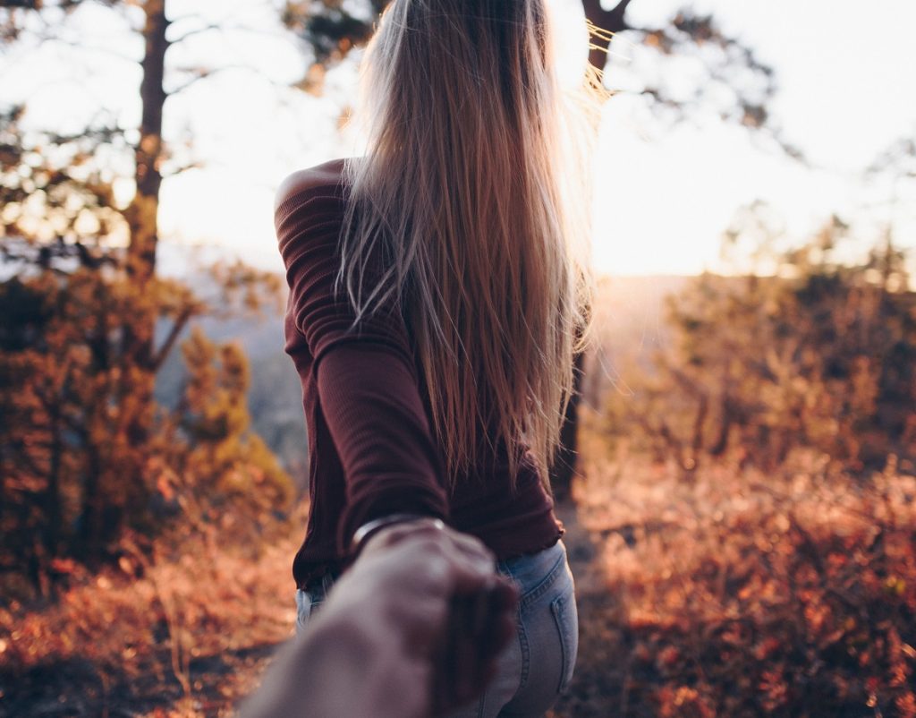 guy holding woman's hand as she walks in front of him