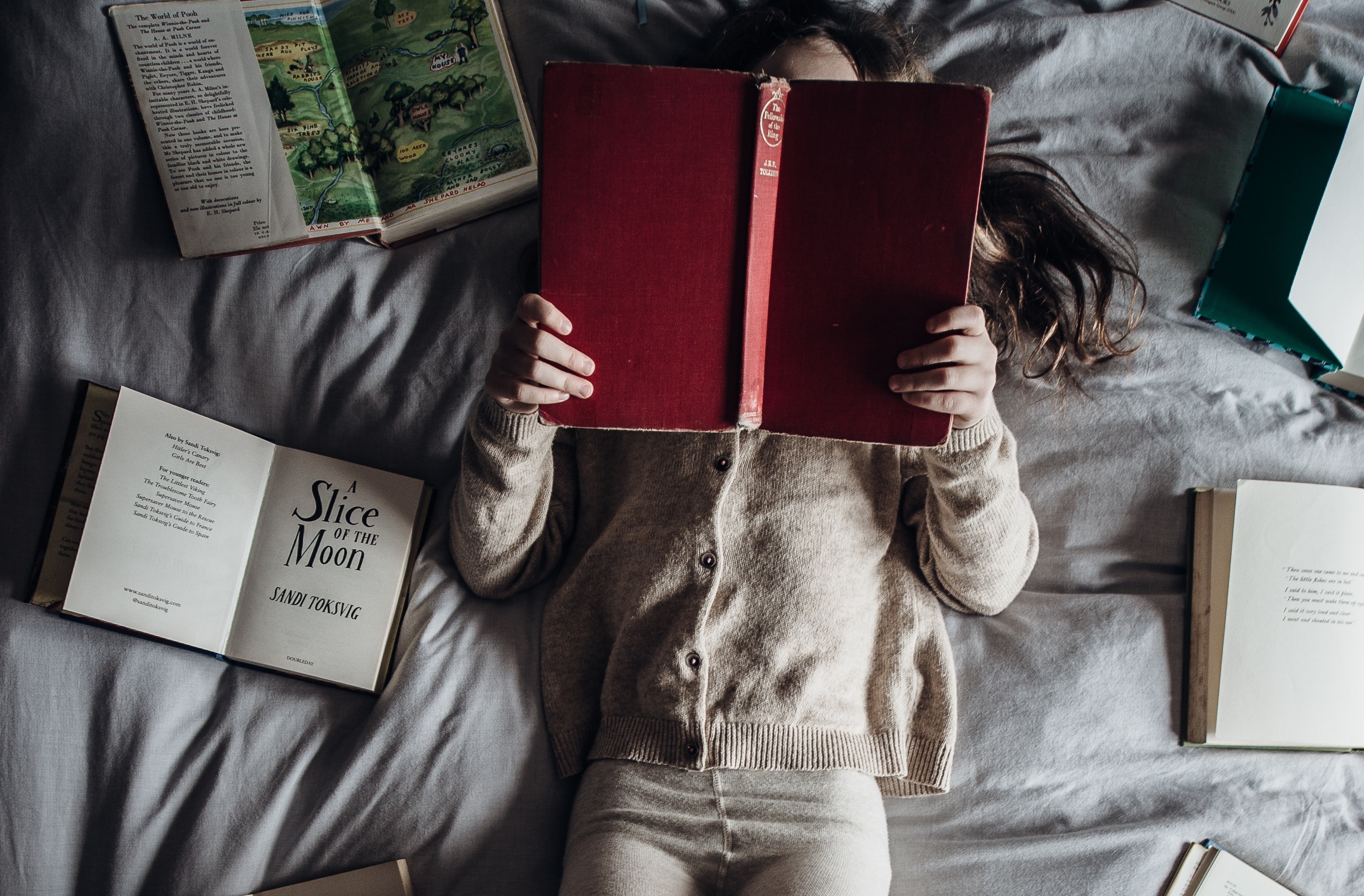 girl holding books on bed