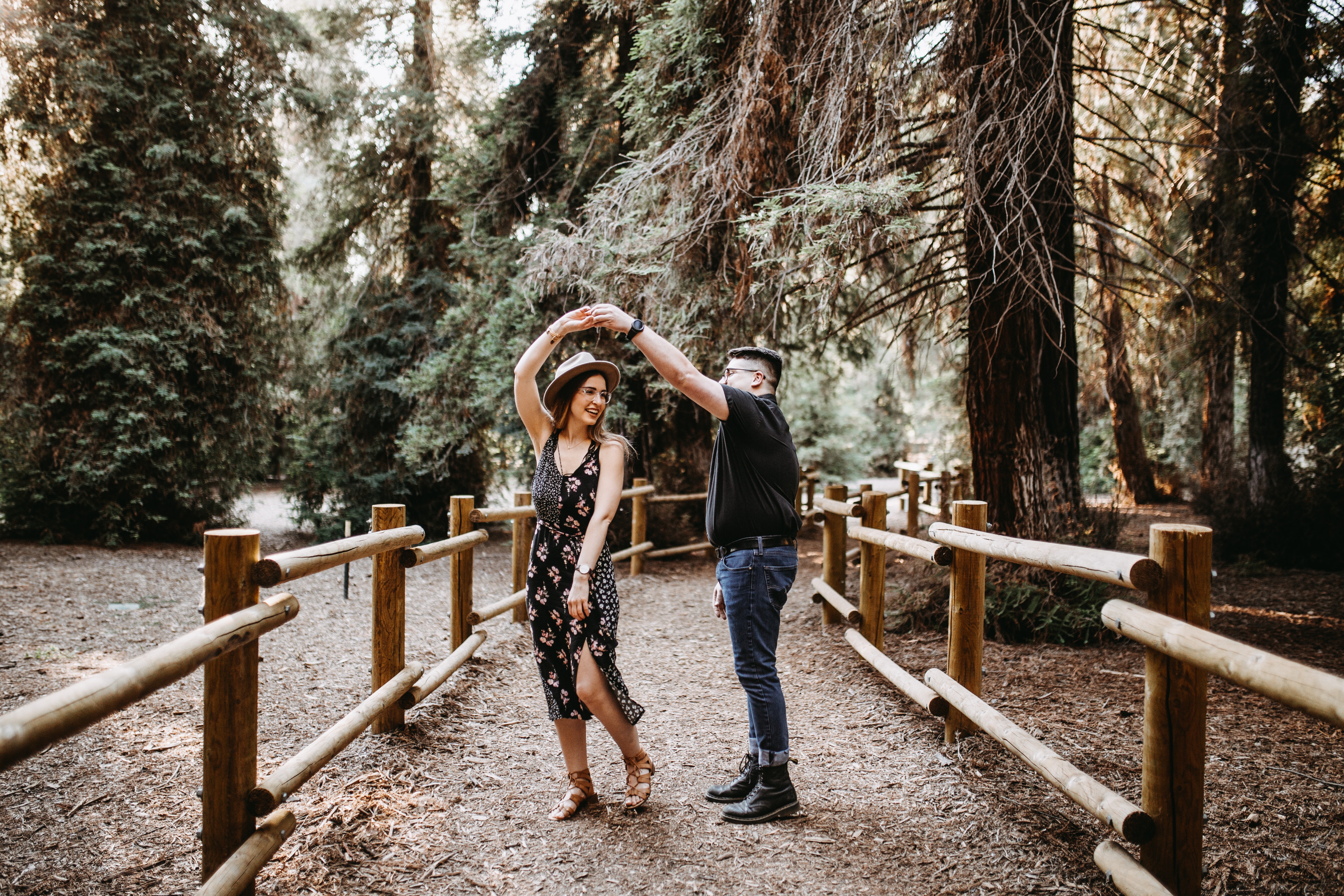happy couple dancing on a bridge in the forest