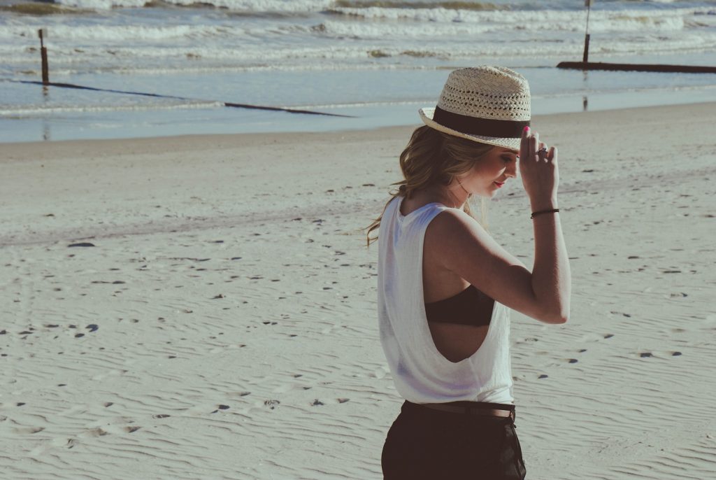 girl with hat in front of beach