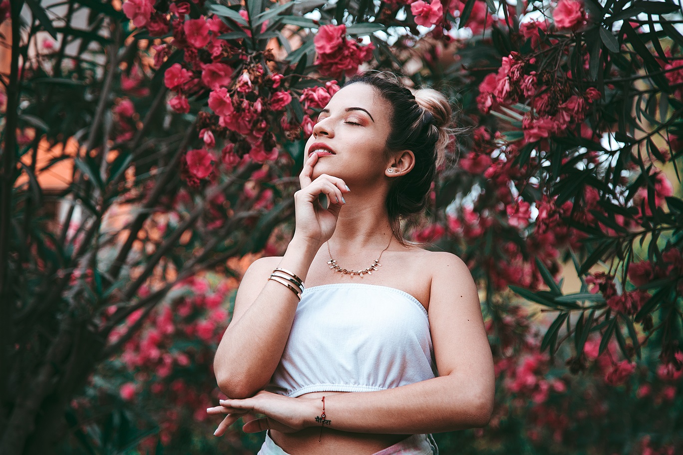 girl in flowers with hand on her lips