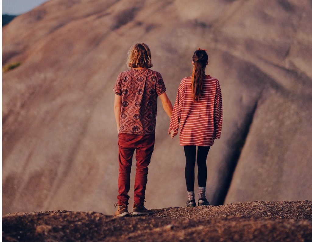 couple holding hands in front of a mountain