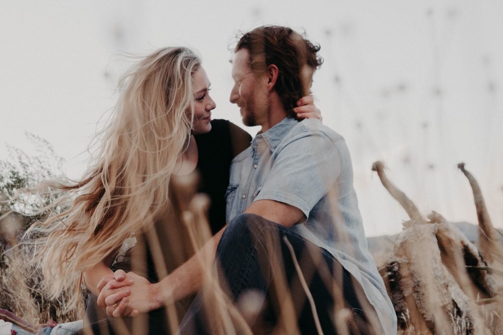 girl with hand around man's neck gently smiling