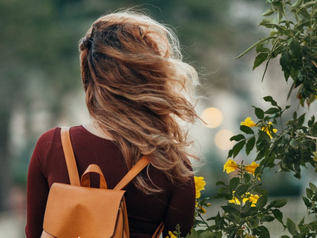 girl with orange backback and hair blowing in the wind