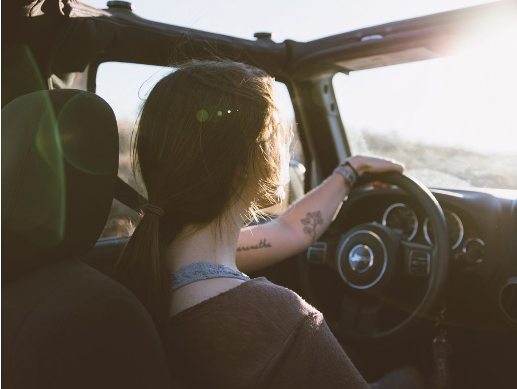 girl driving a car at sunset who can't help but wonder
