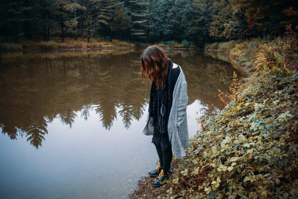 girl standing by a pond looking down