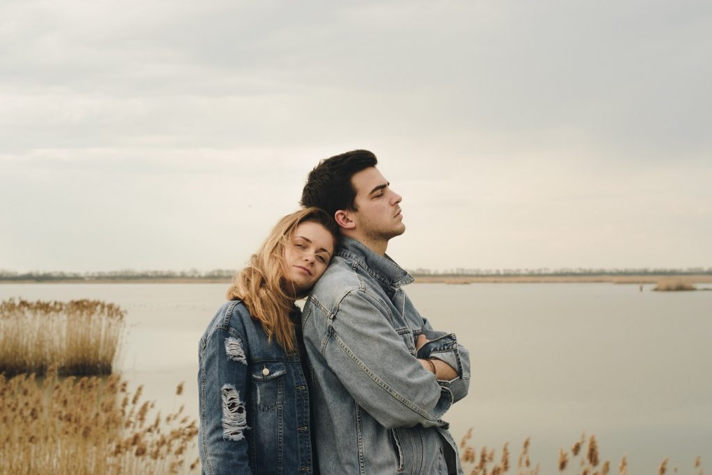 couple leaning against one another by a pond