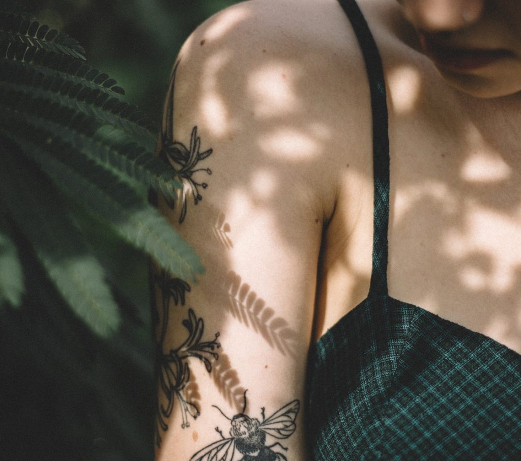 girl with arm tattoos looking down