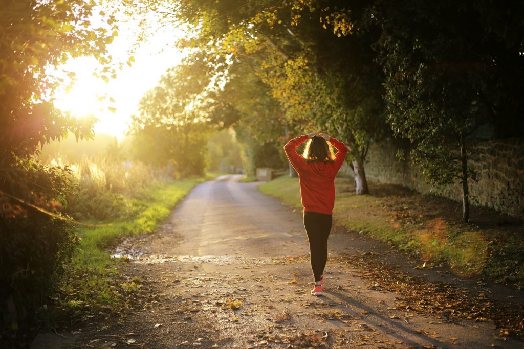 girl walking through sunlight forest path