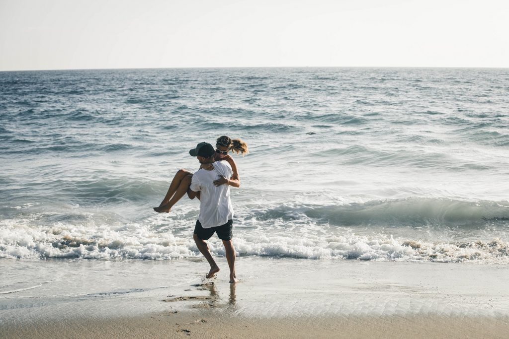 guy holding girl and playfully throwing her in ocean