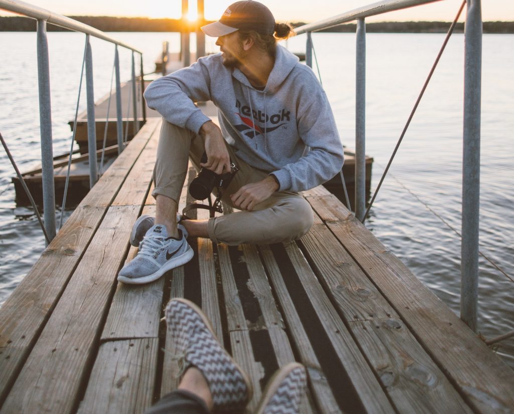 couple sitting separated on a fishing dock