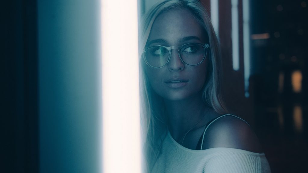 girl with glasses standing in front of a bright light
