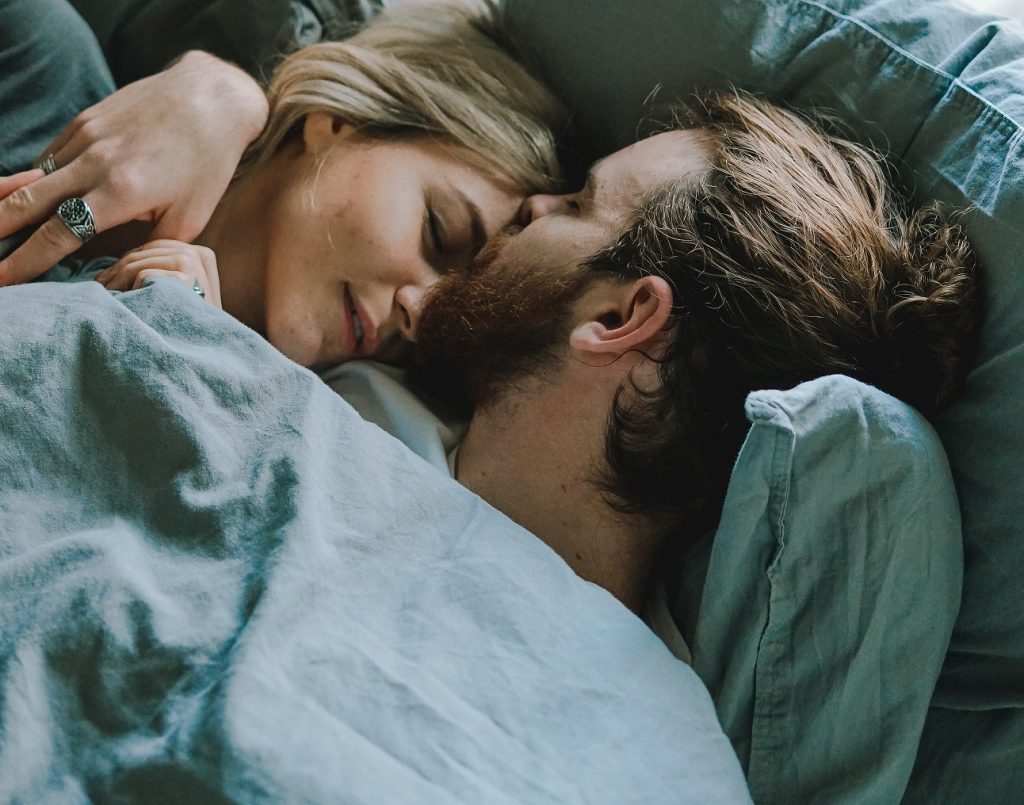 happy and peaceful couple cuddling in bed