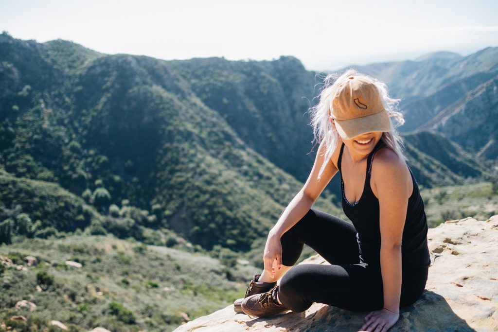 girl with california hat sitting on a mountain