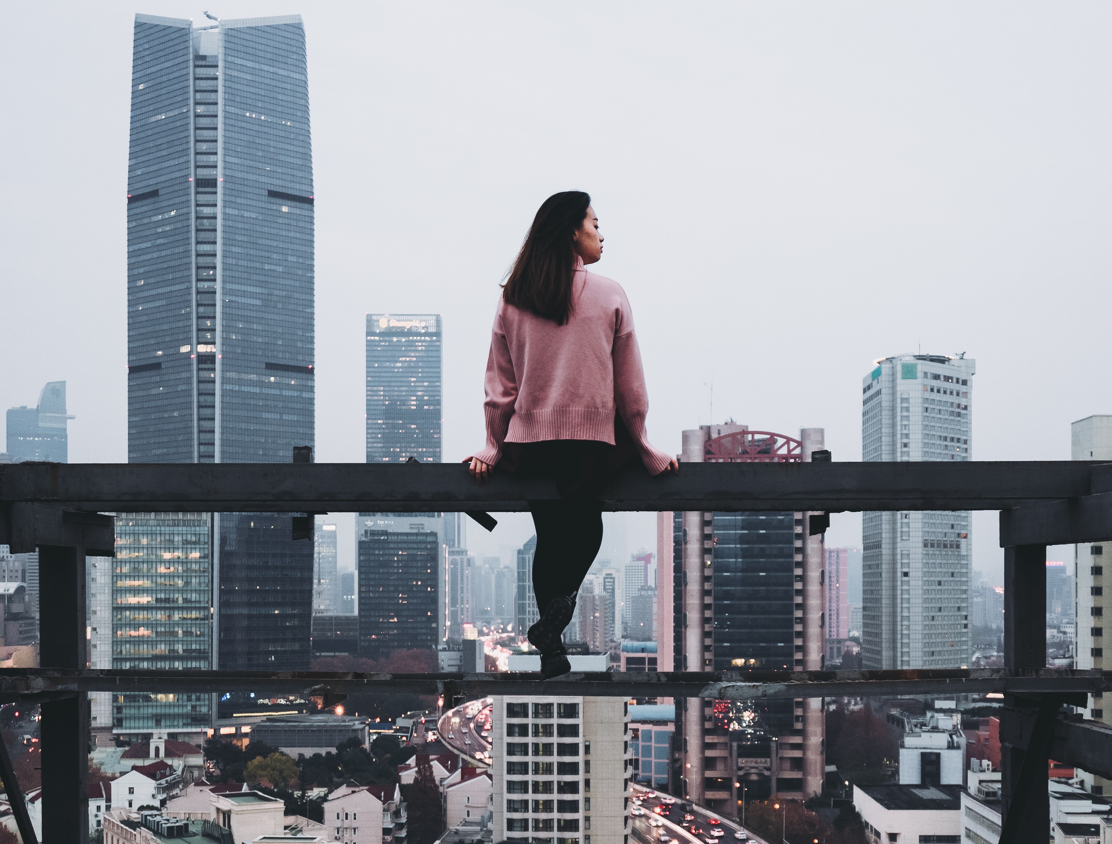 girl sitting on beam in front of skyline