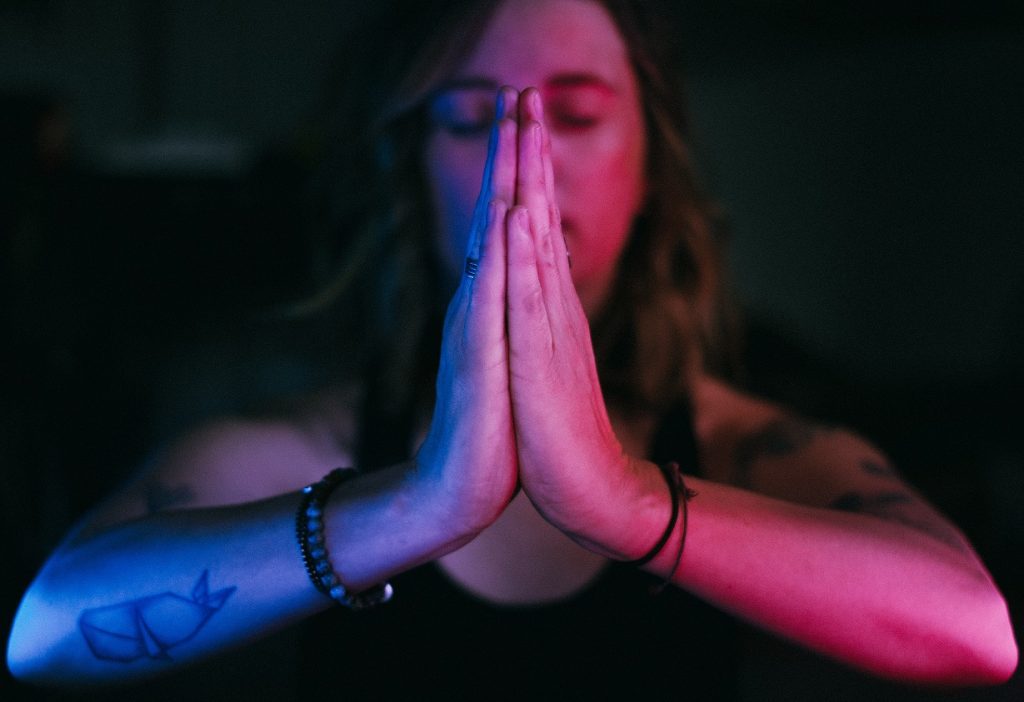 girl with praying hands in dark background