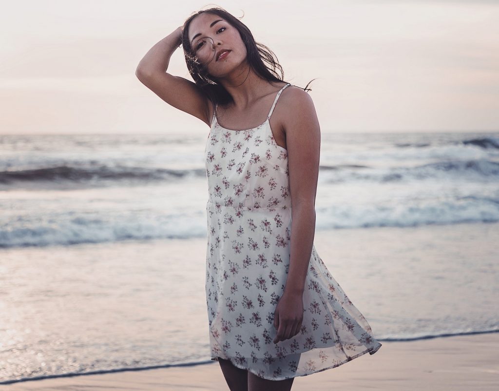 girl with hair in her face standing on the beach