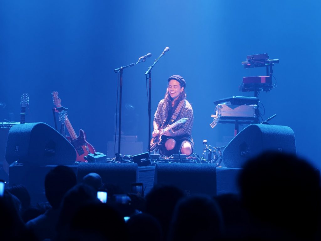 Tash Sultana smiling and playing on stage during show