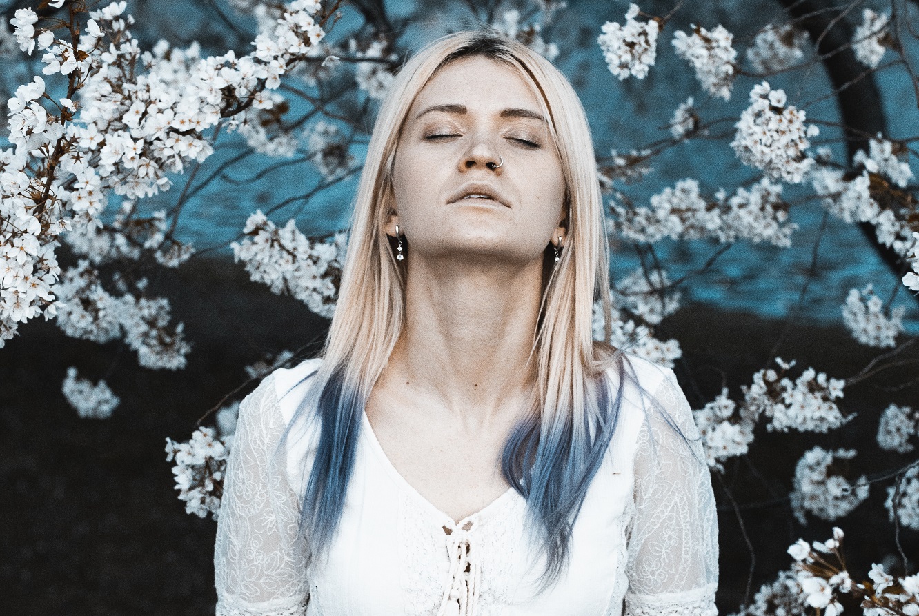 girl with blue hair standing in front of blue and white flowers, fighting feelings of inadequacy