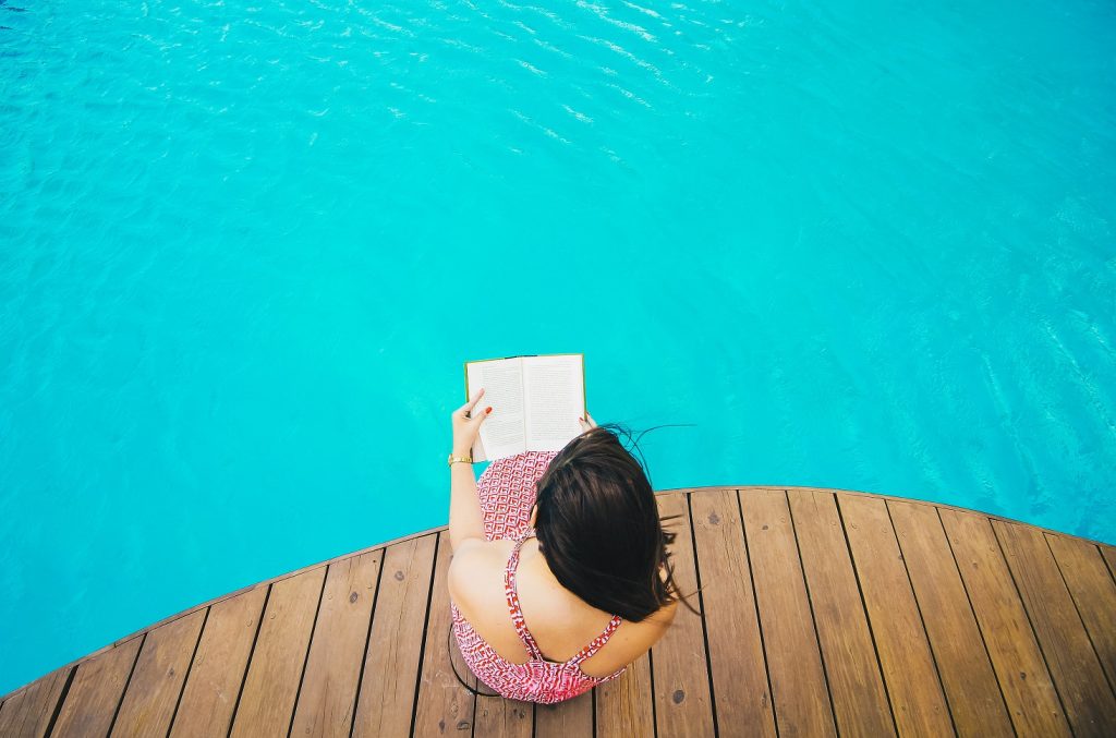 girl reading book by pool, reading list june week 2