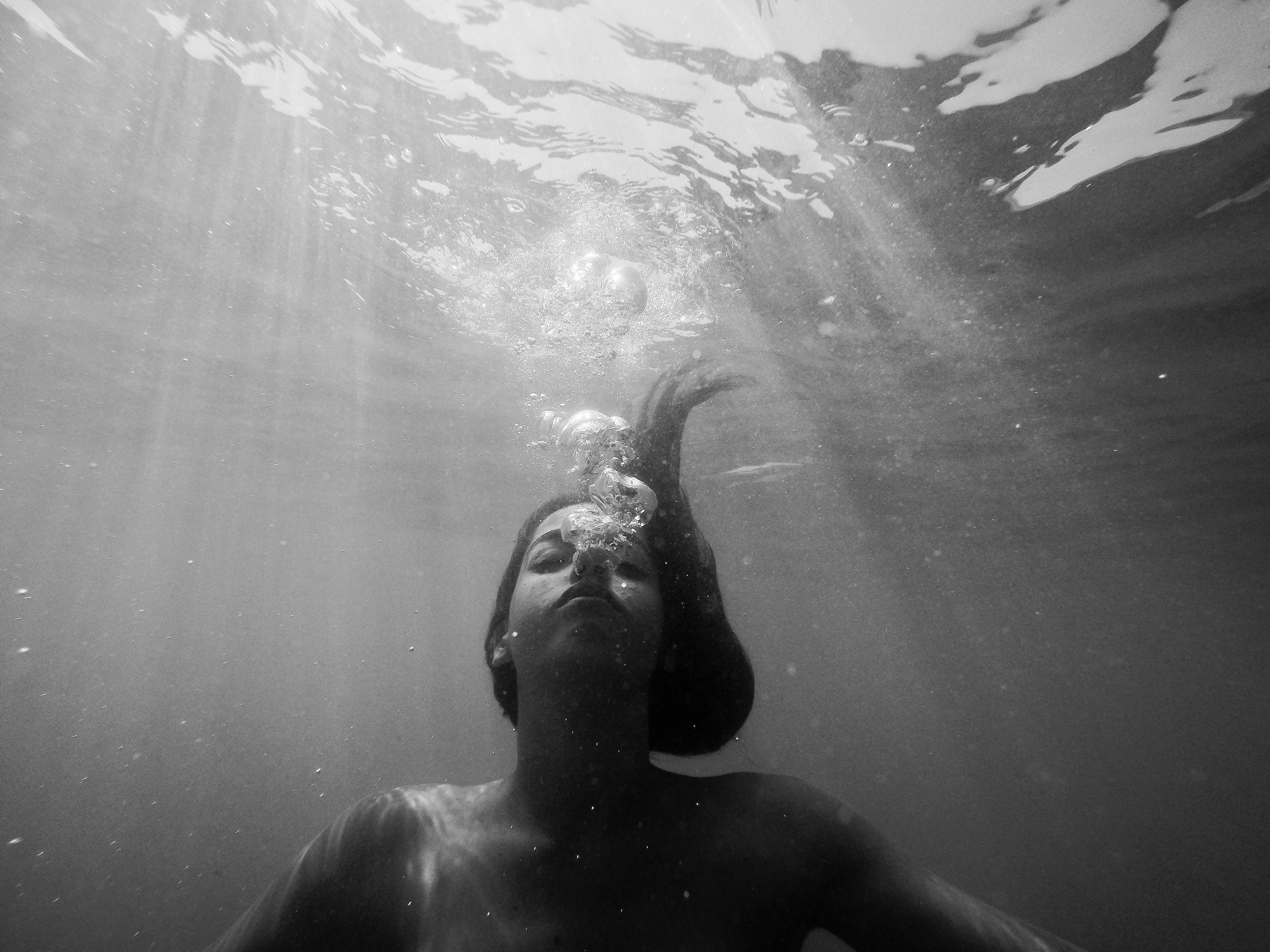 girl underwater blowing bubbles, sad