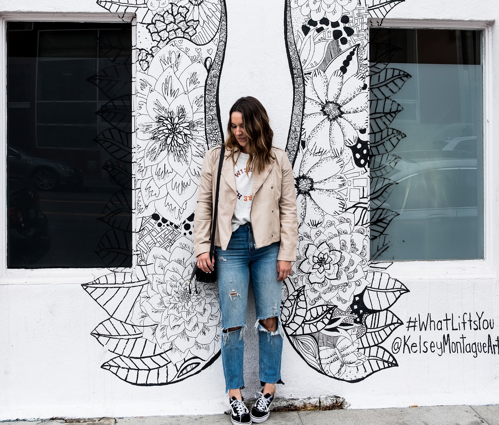 happy woman posing in front of painted wall, find your wings