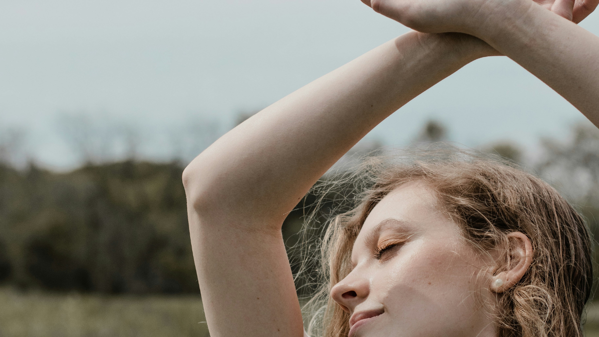 joyful woman with her hands up above her head singing