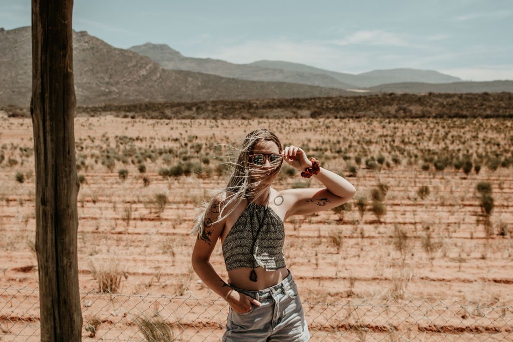 woman with arm up standing in front of desert, let go
