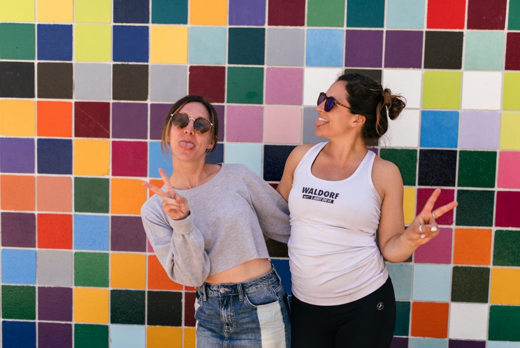 happy girls with peace signs in front of colorful wall