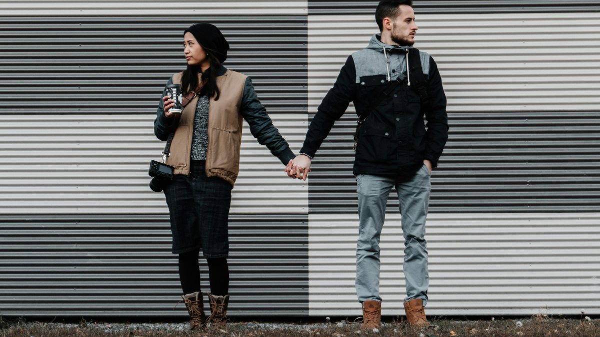 couple holding hands in front of wall