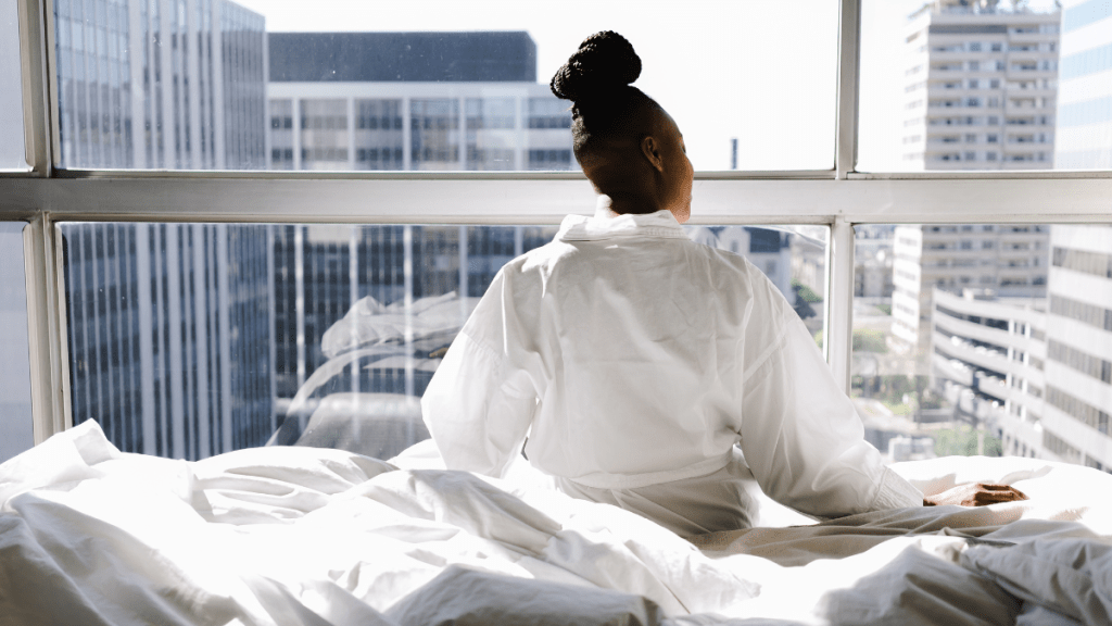 woman sitting on bedroom in her apartment adjusting to letting go