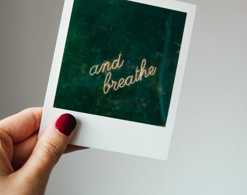 girl holding a just breathe card I will take up space